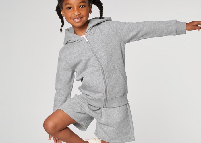 Mädchen in grauem Hoodie und Shorts balanciert spielerisch.
