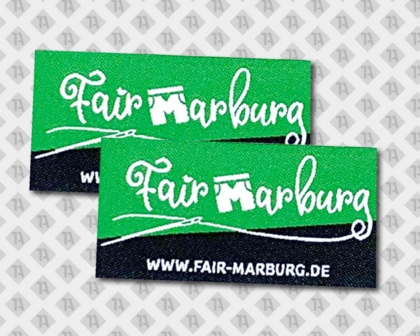 Gewebtes Label Fair Marburg mit URL und grün-schwarzem Hintergrund