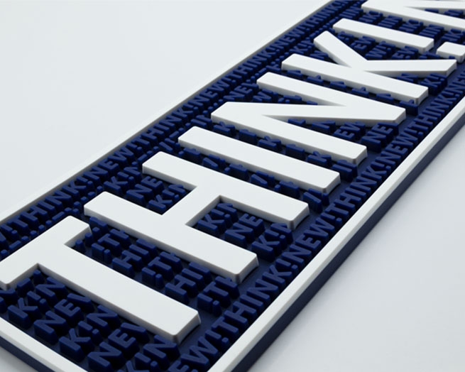Isometrisches Detailbild einer dunkelblauen Barmatte mit weißem "THINK!NEW!"-Schriftzug und Rand