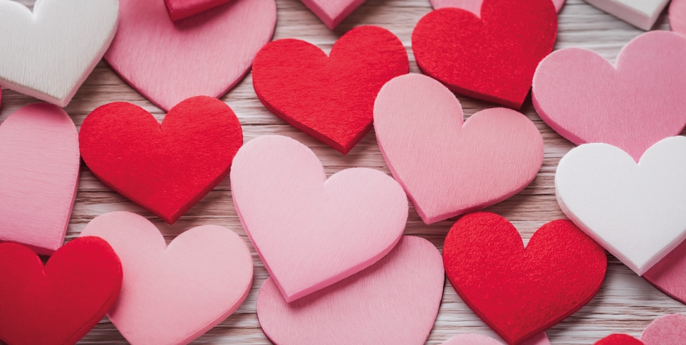 Stimmungsbild zum Valentinstag - einige Holf- und Filzherzen in Rot und Pink auf einem Holzuntergrund