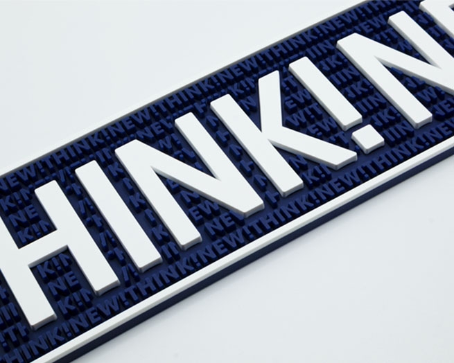 Isometrisches Detailbild einer dunkelblauen Barmatte mit weißem "THINK!NEW!"-Schriftzug und Rand