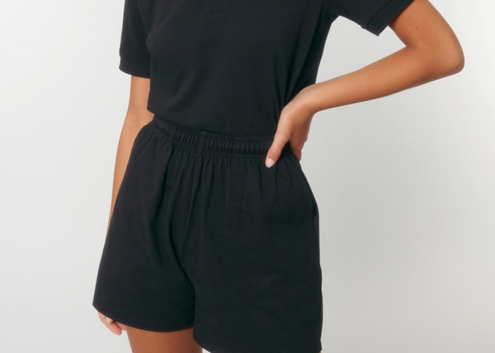Frau steht mit Händen in der Taille und trägt schwarze Shorts.