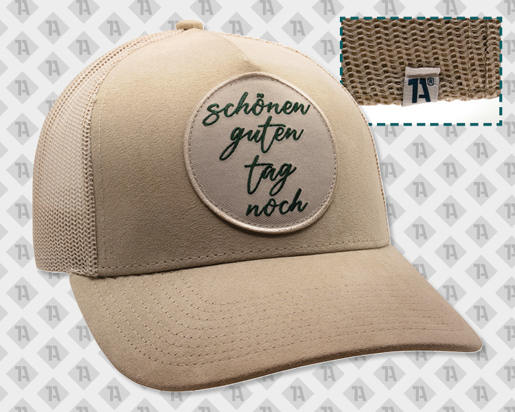 Beige Trucker-Cap mit Mesh, runder Patch, grüner Script-Schriftzug „schönen guten tag noch“, kleiner TA-Label am Netz