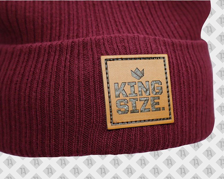 Bordeauxrote Beanie mit eckigem Leder-Patch „KING SIZE“, geprägt und mit Ziernaht.